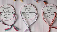 three handmade tags with words and tassels attached to them on a wall