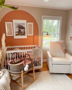 a baby's room with an orange wall and white furniture