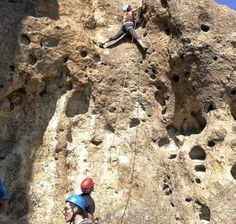 people climbing up the side of a mountain with helmets on and ropes attached to them