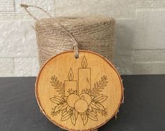 a wooden ornament with a candle and flowers on it sitting next to twine