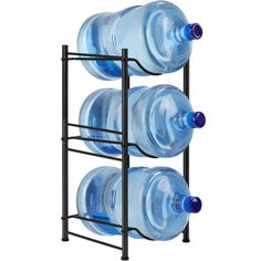 three plastic water bottles are on a black rack and one is empty, the other two have blue lids