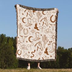 a person standing in front of a blanket that has various desert and cactus designs on it