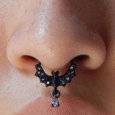 a close up of a person's nose with an earring in the shape of a bat