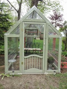 a small green house sitting in the middle of a yard