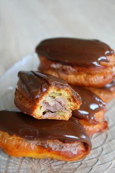 three chocolate covered donuts sitting on top of a glass plate