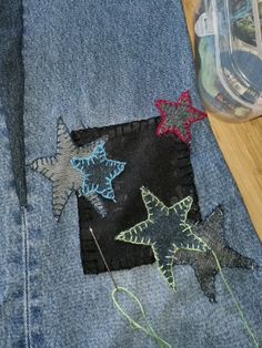 the jeans are decorated with different colored stars and thread on them, along with a plastic container