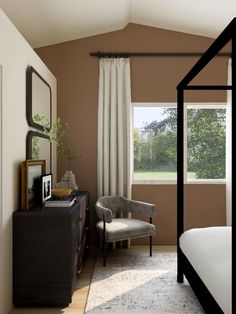 a bed room with a neatly made bed next to a window and a chair in front of it