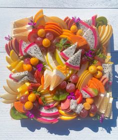 a platter filled with lots of different types of fruit on top of a white table