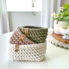 three knitted baskets sitting on top of a table next to a potted plant