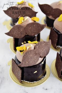 chocolate cupcakes decorated with yellow flowers on top of each other, sitting on gold plates