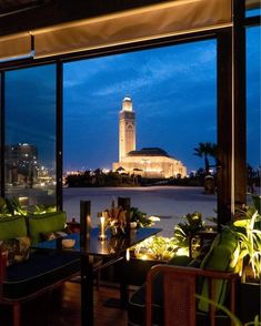 a restaurant with large windows looking out at the water and a clock tower in the distance