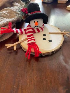 a snowman is sitting on top of a piece of wood