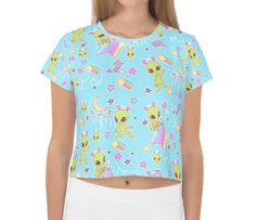 A pastel blue alien shirt featuring little green aliens who are only out to abduct your heart and bring a little shock of pastel to your life. This cropped t-shirt, which has a slightly silky, knit feel, also has contrasting rainbows and stars. It's unisex and fits loose, making for a comfy casual addition to your fairy kei and decora wardrobe while being low-key. Apparel and bedding ship separate from handmade items. Delivered in 2-4 weeks. The colors print more pastel than the items I make mys Playful Fitted Tops With Character Print, Fitted Playful Tops With Character Print, Light Blue Cartoon Print Short Sleeve Top, Blue Top With Funny Print, Fun Fitted Tops With Character Print, Fitted Playful T-shirt With Cartoon Print, Fitted Blue Tops With Funny Print, Fitted Blue Top With Funny Print, Summer Unicorn Print Crew Neck Top