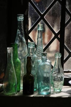 there are many different colored glass bottles on the window sill in front of it