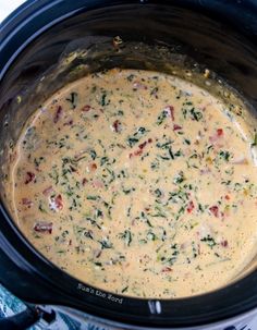 a crock pot filled with cheese and vegetables on top of a blue cloth covered table