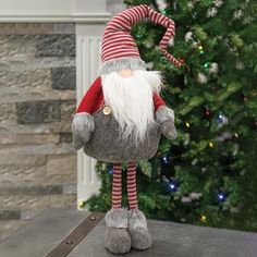 a stuffed santa claus doll sitting on top of a table next to a christmas tree