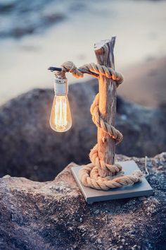 a light bulb is attached to a rope on top of a rock by the ocean