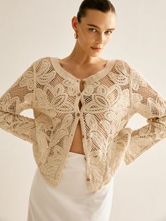 a woman in a white dress is posing with her hands on her hips and wearing a crochet jacket