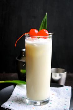 a tall glass filled with milk and topped with a cherries garnish on top