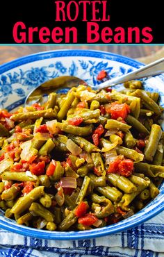 a blue and white bowl filled with green beans on top of a table next to a spoon