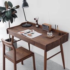 a wooden desk with two chairs next to it and a potted plant in the corner