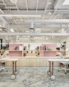 an office with pink and white walls, desks and chairs in the foreground