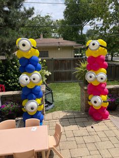 two large balloons with eyes on them in the shape of cartoon characters are sitting next to a patio table and chairs