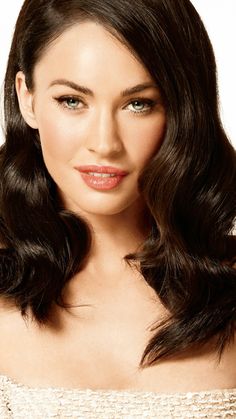 a woman with long dark hair wearing a strapless top and lipstick on her lips