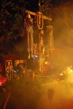 a group of people standing in front of a cross at night with lights shining on them