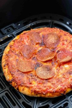 a pepperoni pizza sitting on top of a grill