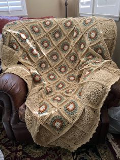 a crocheted blanket is sitting on a leather chair