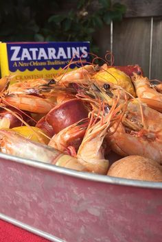 a large metal container filled with shrimp and other food items next to a box of zaatans