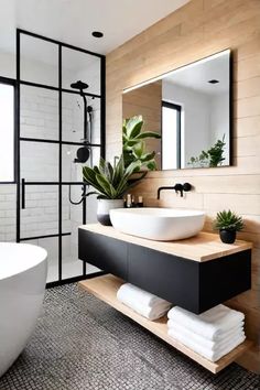 a white bath tub sitting next to a bathroom sink under a mirror and a potted plant