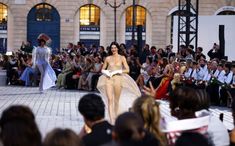 models walk down the catwalk at a fashion show in front of a crowd of people