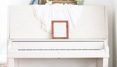 a white piano sitting in the corner of a room with books on top of it