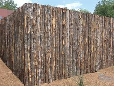 a large wooden fence in the middle of a field with grass and dirt around it