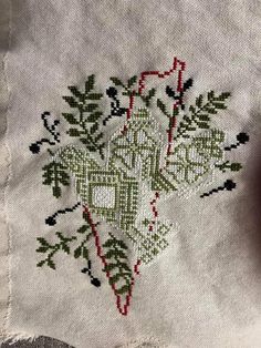 an embroidered piece of cloth with green and red designs on the side, sitting next to a pair of scissors