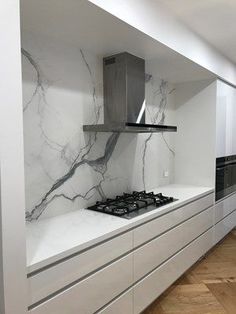 a modern kitchen with marble counter tops and white cabinetry, along with hardwood flooring