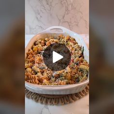 a dish filled with pasta and sauce on top of a table next to a marble counter