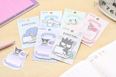 some cute stickers are sitting on a table next to a pen and notebooks