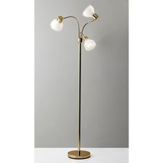 three light floor lamp in brass finish with white glass balls on the top and base