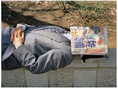 a man in a suit and tie laying on a brick wall next to a newspaper