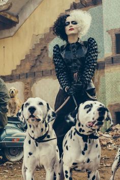 a woman riding on the back of two dalmatian dogs