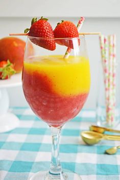 two strawberries are on the top of a drink in a wine glass with liquid