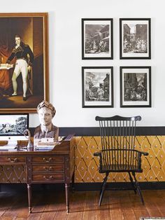 a room with pictures on the wall and an antique chair in front of a busturine