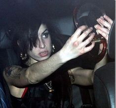 a woman in a car with her hand on the steering wheel