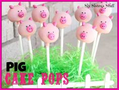 pig cake pops are sitting on top of green grass in front of a brick wall