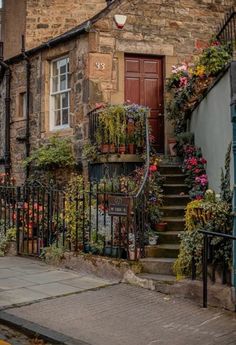 an old stone building with flowers growing on it's balconies and stairs