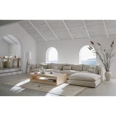 a living room filled with furniture and lots of windows next to a large white wall