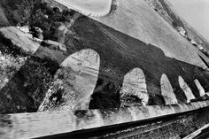 an old black and white photo of the side of a bridge with water flowing over it